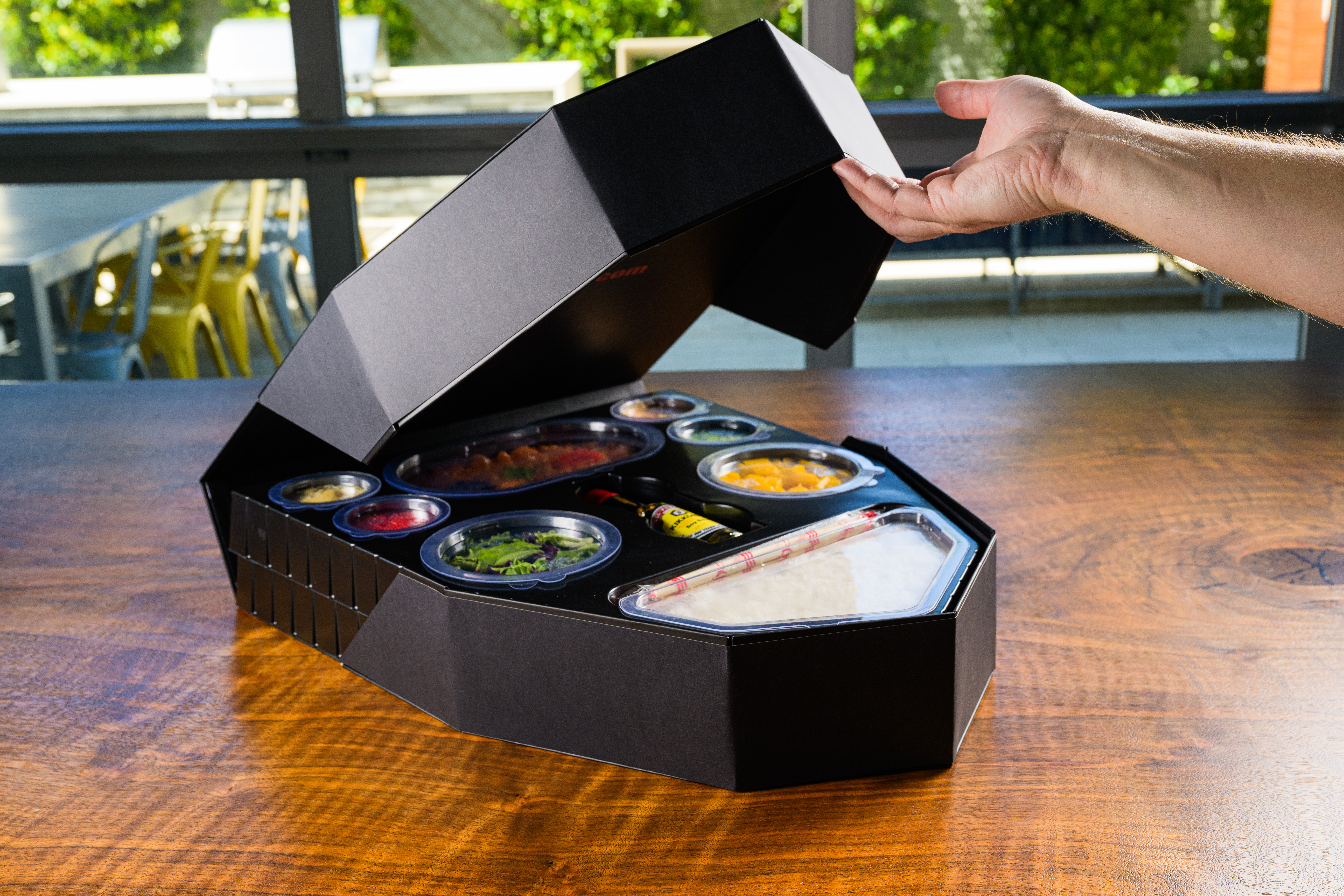 Hand opening a Sushi Boat box revealing compartments inside