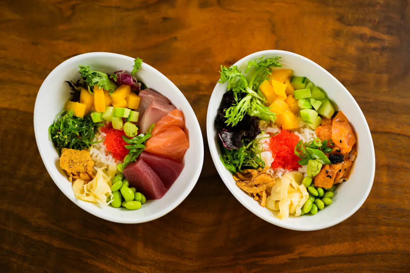 Two poke bowls from above with colorful toppings